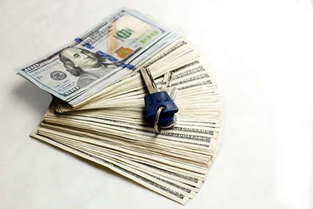 Stack of new hundred-dollar banknotes with keys on white background. Earning income money from real estate transactionsの写真素材