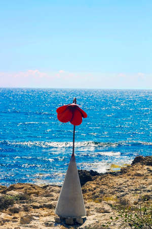 Street lamp in form of red poppy flower on beach by sea. Flower lampの写真素材