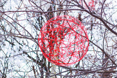 Christmas decoration red ball of yarn hanging on tree in winter parkの写真素材