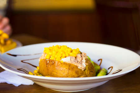Stuffed potato with tuna and sweetcorn on white plate selective focusの写真素材