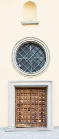 Old wooden door and round window with metal grid