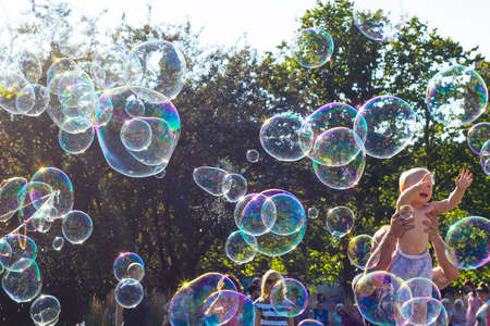 Warsaw, Poland - 30 July 2017: Small happy child playing with big soap bubbles against blue skyのeditorial素材