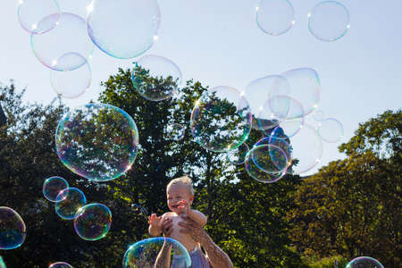 Warsaw, Poland - 30 July 2017: Small happy child playing with soap bubbles against blue skyのeditorial素材