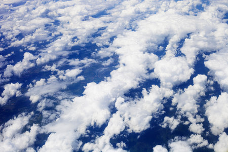White fluffy clouds in blue sky, top view. View from airplane window