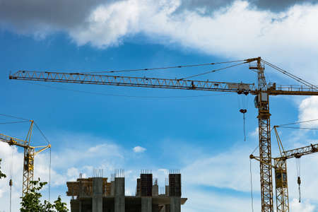 Tower crane by blue sky. Yellow high construction crane building houseの写真素材