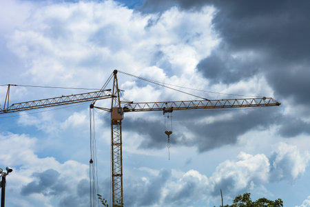 Tower crane by blue sky. Yellow high construction crane building house