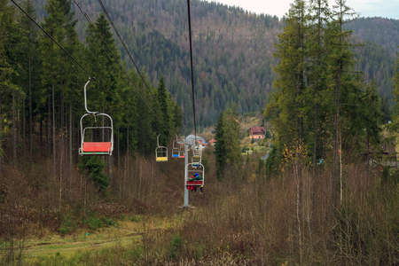 Old ski lifts with people ride through pine forest, Lviv region in Ukraineの写真素材