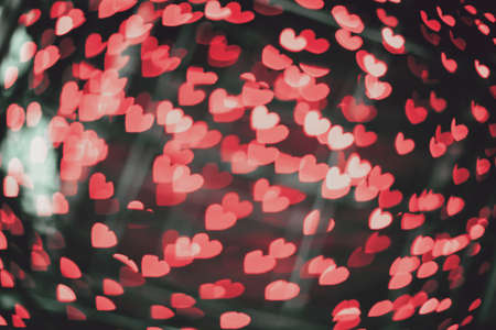 Valentines day blurry red lights. Blur background with lot of glowing heart bokeh. Defocus abstract romantic shine wallpaperの写真素材