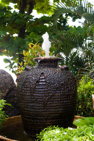 Fountain with water in the form of large amphora in summer garden