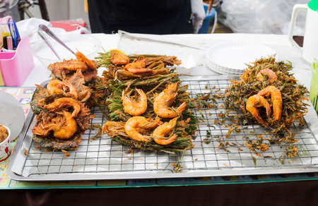 Delicious King prawns fried in batter on dish of green seaweed, healthy seafood. Barbecue srimps prawn tempura on street market in Phuket, Thailandの写真素材