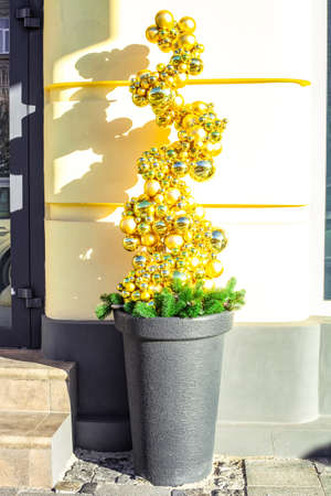 Artificial Christmas tree made entirely of golden baubles in pot. Funny xmas from shiny gold balls in flowerpot. Ornament covered alternative potted tree from bright glass toys, creative street decorの写真素材