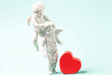 Angels baby and red heart on blue background. White little cupids flying in the sky, old fashioned...