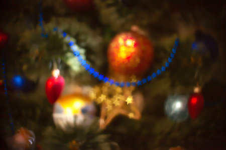 Blurred background with toys on christmas tree. Abstract defocused shiny bright backdrop. Festive stars bokeh effect, xmas vibrant glowing ornamentの写真素材
