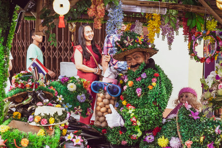 Phuket, Thailand - February 25, 2018: Elderly man in green grass funny attire. Flowers man with jar of eggs on street marketのeditorial素材