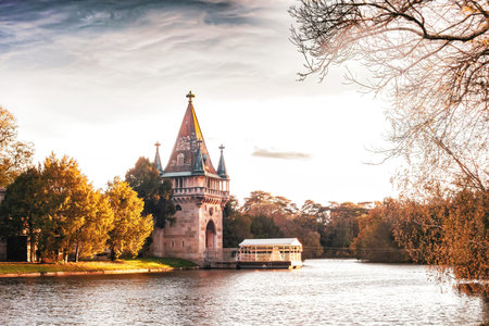 Medieval Franzensburg castle and small ferry on lake in autumn Laxenburg park, Lower Austria. Romantic gothic water palace on artificial island in fall Schlosspark Laxenburg golden hour parklandの写真素材
