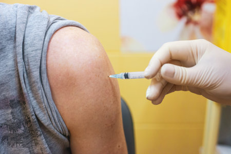 Doctor administering a flu injection to a patient in a clinic office. Nurse in surgical glove injecting a vaccine on the arm in a hospital room. Influenza shot, taking a blood test. Hand holding a plastic syringe.の写真素材