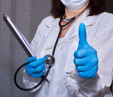 doctor in a white coat with a phonendoscope shows a hand gesture, thumb upの写真素材