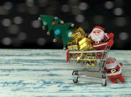 santa claus carrying christmas gifts and a tree in a cartの写真素材