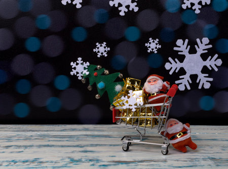santa claus carrying christmas gifts and a tree in a cart bokeh background, christmas background,...