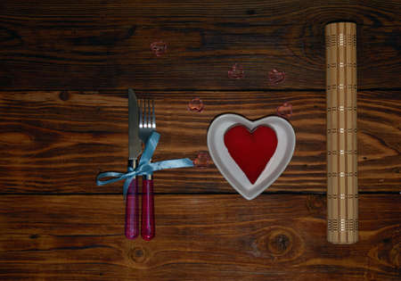 cutlery plate in the form of a heart on a wooden background background with a plush heart in it, glass hearts on the tableの写真素材