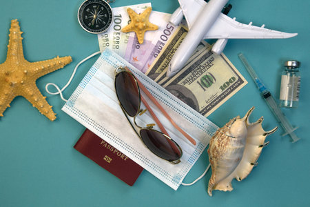 airplane model, passport with covered medical mask, ampoule with vaccine and syringe, dollar and...