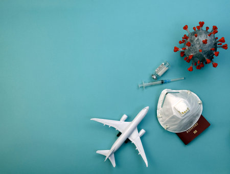 model of airliner, passport with mask covered with respirator, ampoule with vaccine and syringe and...