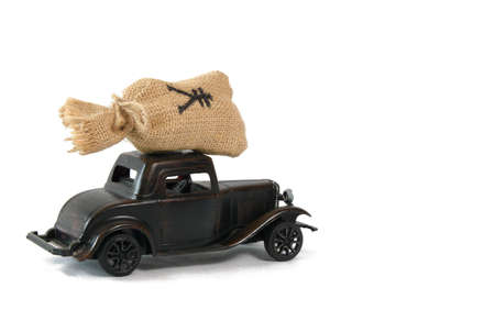 brown toy car carrying a bag of yuan currency on the roof, on a white background, isolate, conceptの写真素材