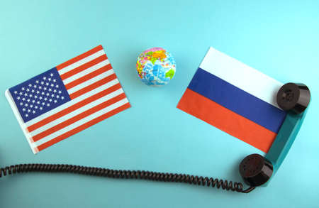 concept, telephone conversations of the presidents of the United States and Russia, a telephone receiver on the background of the flags of the two countries on a turquoise backgroundの写真素材