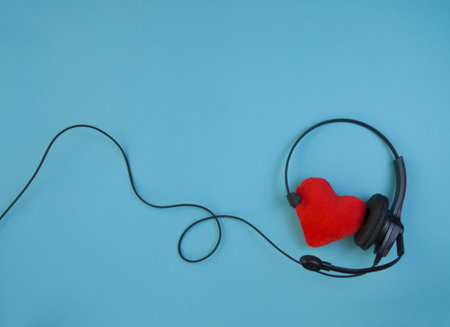 earphone with microphone and heart model on a blue background, top view