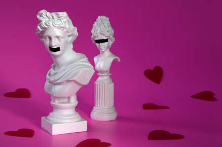 sculptures, busts of a man and a woman with taped eyes and mouth, on a pink background, conceptの写真素材