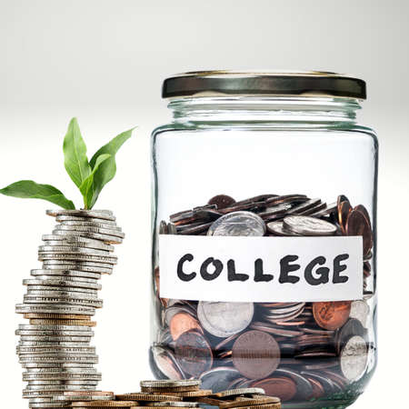 Stack of growing coins with a jar of coins saving for collegeの写真素材