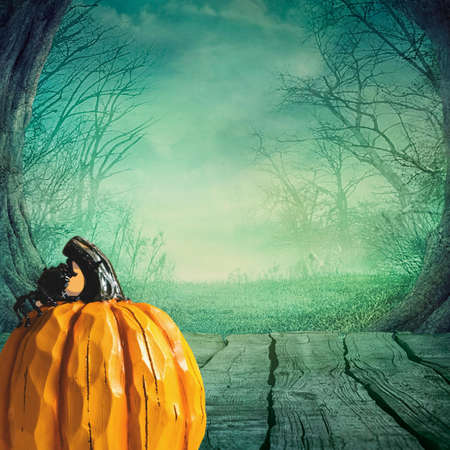 Halloween night with pumpkin sitting on a wood boat dock with a misty blue green background over the waterの写真素材