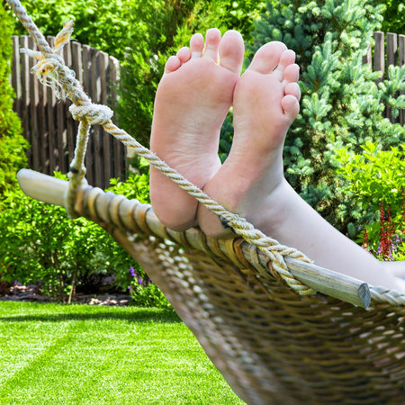 A person relaxing in the backyard in a hammock with legs and feet shownの写真素材