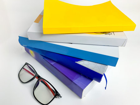 pile of books and glasses on a white background
