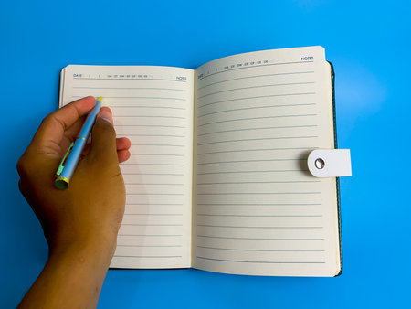 Hand writes in a notebook on a blue background