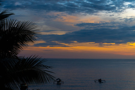 sea â€‹â€‹view at sunset with orange sky and coconut leaves in the foreground