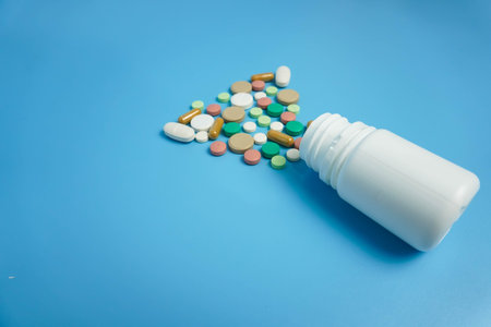 close up Assorted colorful pharmaceutical medicine pills, tablets and capsules and white bottles on...