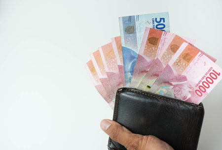 holding a wallet with indonesian money rupiah looking out of the wallet white backgroundの写真素材