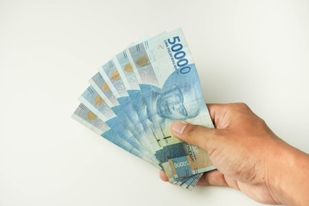male hand holding a lot of indonesian money rupiah on a isolated white background. business concept...