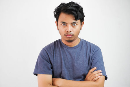 Image of angry displeased asian man standing and crossing arms with outfit casual isolated over...