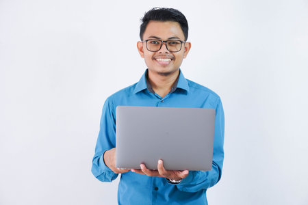 smiling or happy asian businessman with glasses holding laptop wearing blue shirt isolated on white...