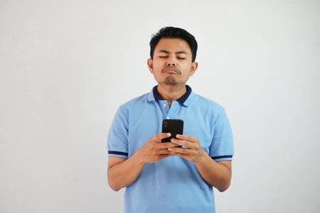 sad face with holding phone young asian man wearing blue polo t shirt isolated on white background....