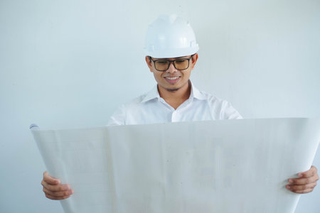 young asian male architect engineer smiling and Holding engineering blueprints isolated on white background.の写真素材