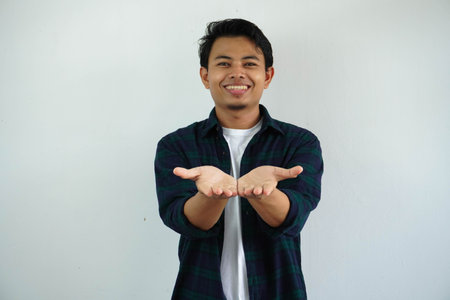 young asian man smiling happy with both hand doing giving something pose isolated on white background.の写真素材