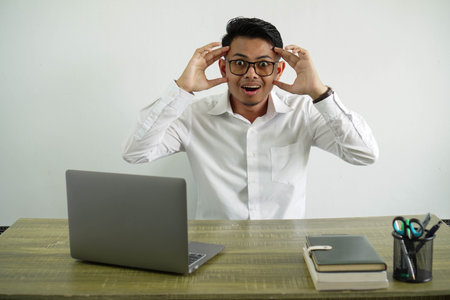 young asian businessman in a workplace with surprise expression, wear white shirt with glasses...