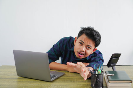 Tired perplexed young asian man sit work at wooden desk with pc laptop. Achievement business career...