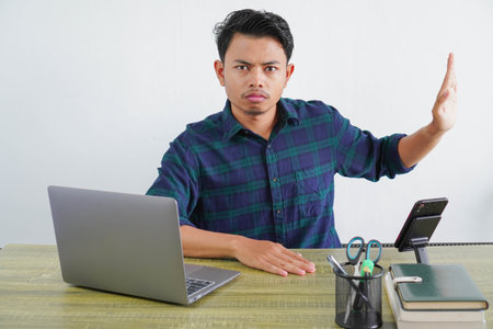 young asian man sit work at wooden desk with pc laptop. Achievement business career lifestyle concept. showing stop gesture aside with palmの写真素材
