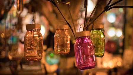Multi-colored mason jars illuminated at night in front of storeの写真素材
