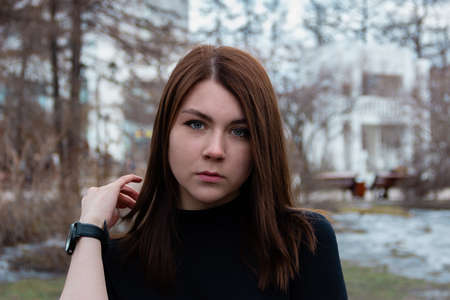 A woman is serious, she is standing in front of the camera, touching his hair. Made outside in the Park.の写真素材