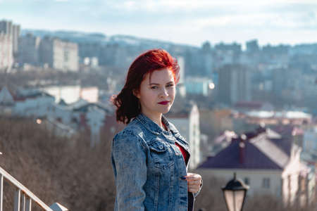red hair model wear blue denim jacket and red dress. outdoors. High fashion.の写真素材